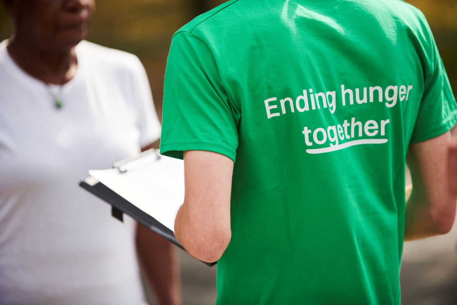 People talking with back of T-shirt that reads Ending Hunger Together
